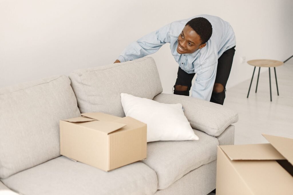 Young man smiling while arranging his living room in daylight