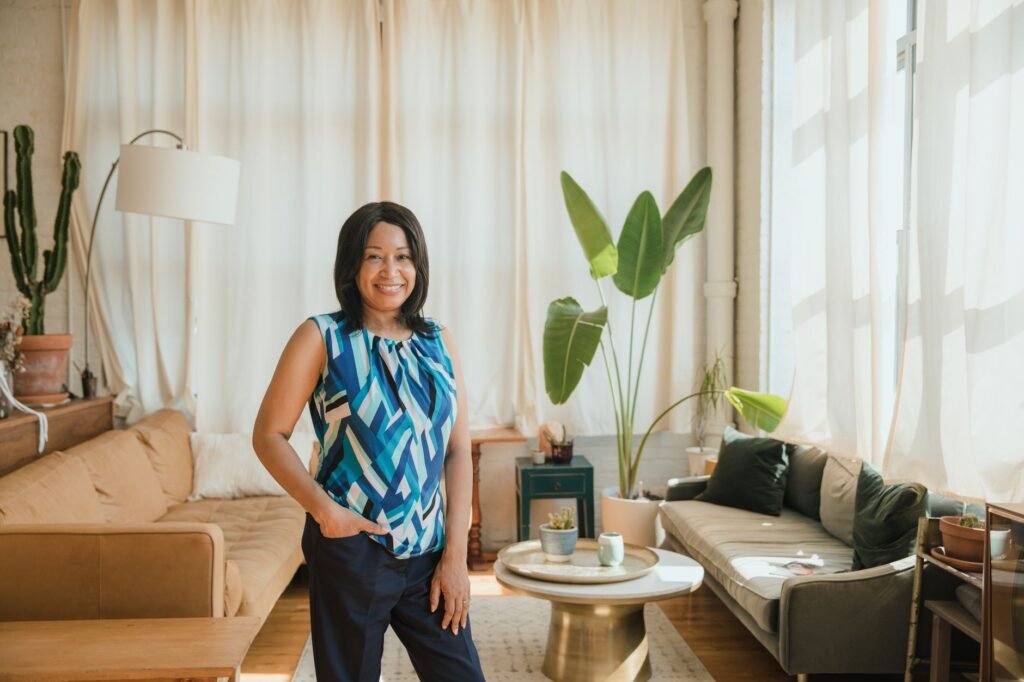 Smiling woman standing confidently in a bright, sunlit living room