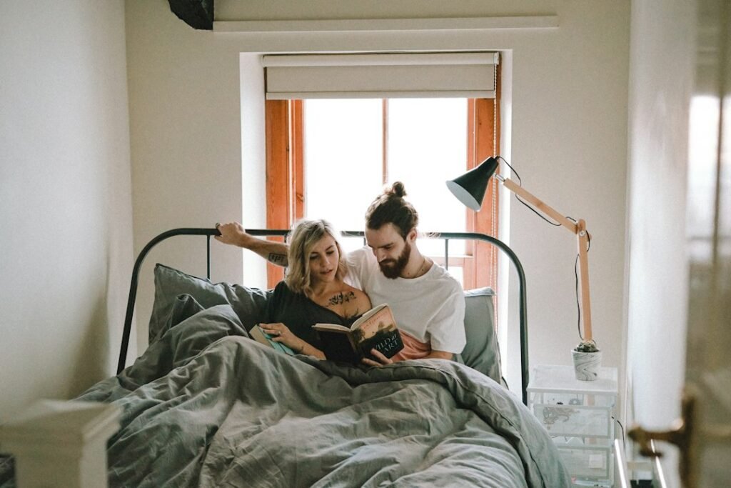 Couple relaxing on bed reading together in daylight