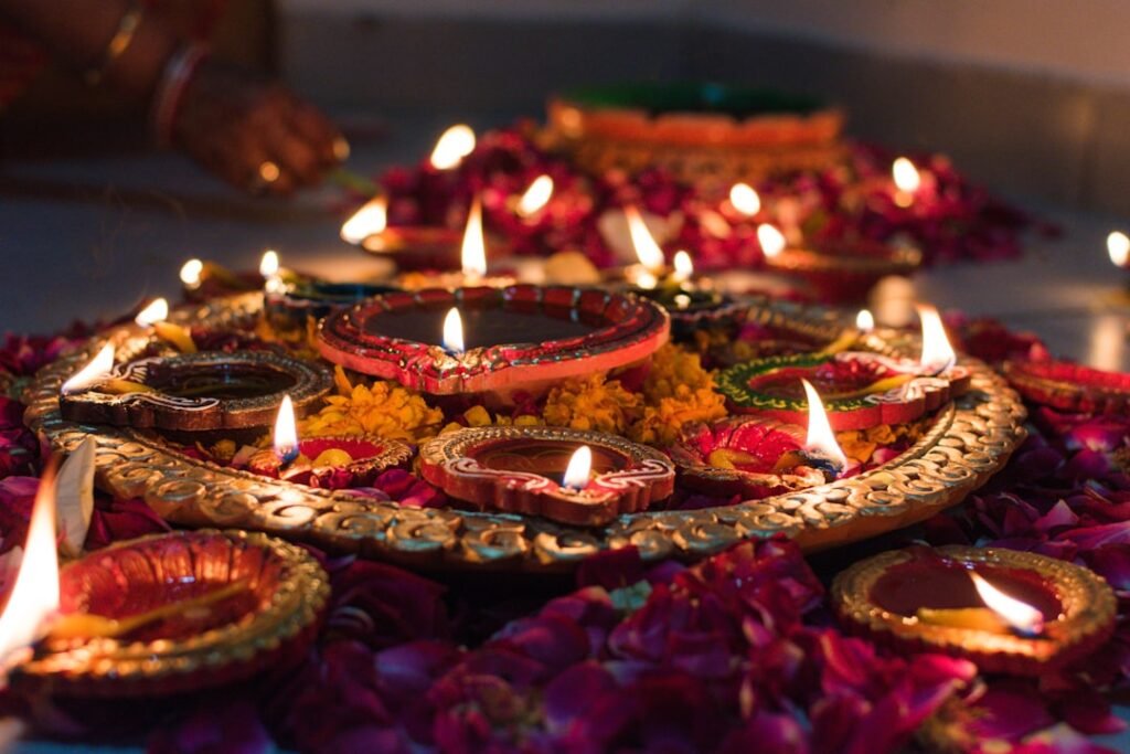 Lit clay diyas and candles arranged on a decorative tray for Diwali