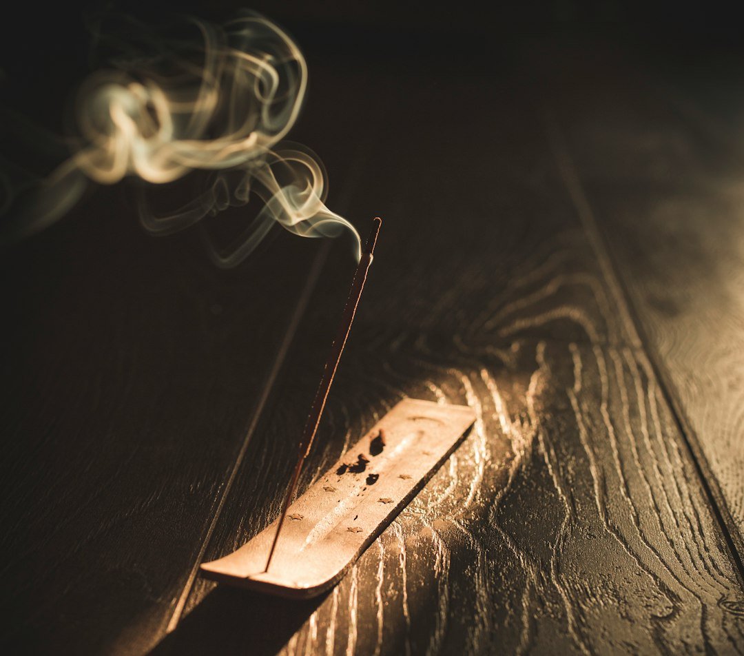 Burning incense stick with rising white smoke