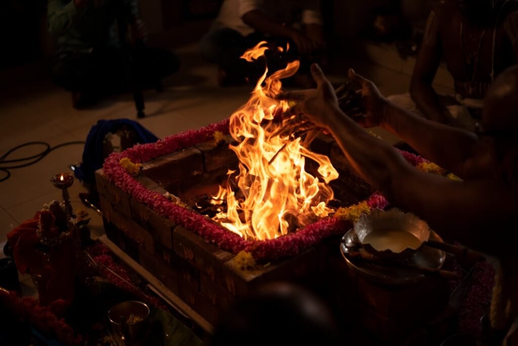 Priest performing a havan fire ritual, adding wood and ghee to the sacred fire