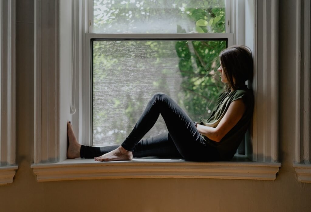 Woman sitting calmly by a sunlit window