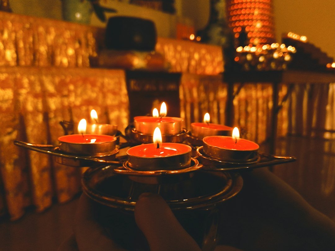 Tray of lit oil lamps held in a dark temple