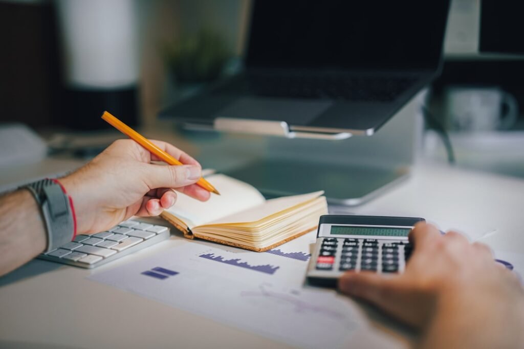 Person writing numbers and calculations at a desk in daylight