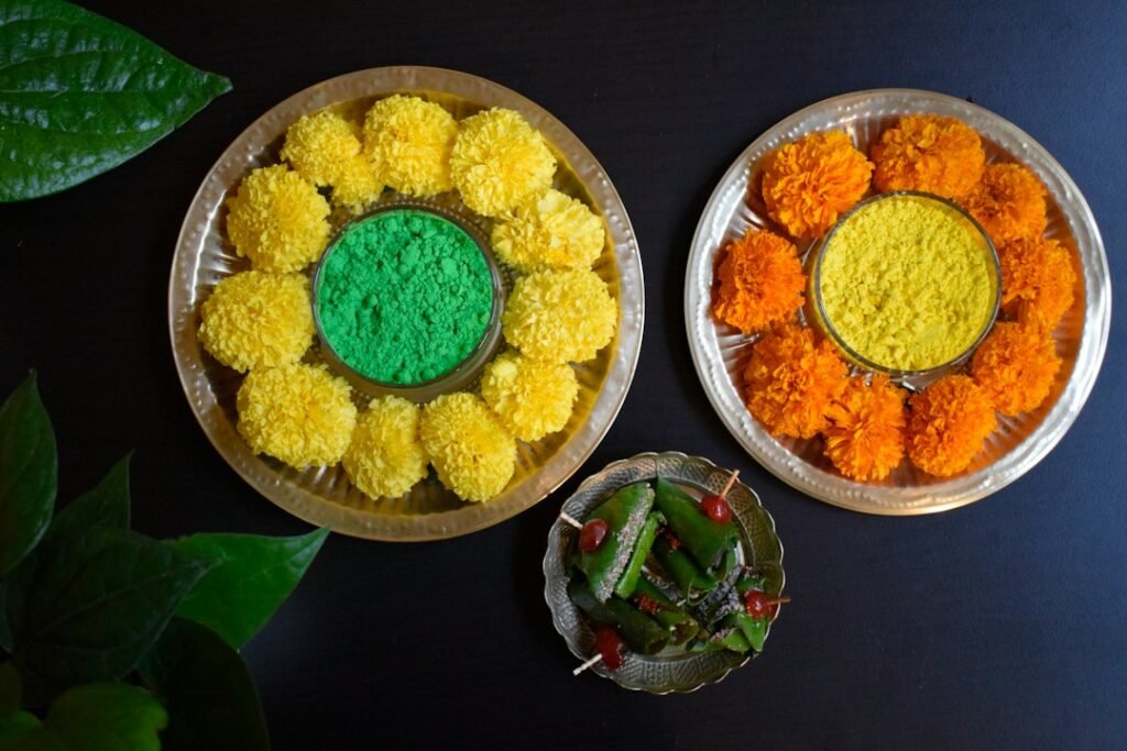 Festive table with plates of coloured gulal powder, marigold flowers and sweets