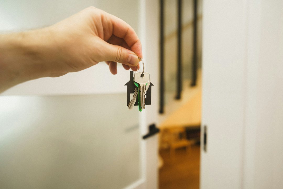 Hand holding a key in the front door of a new home