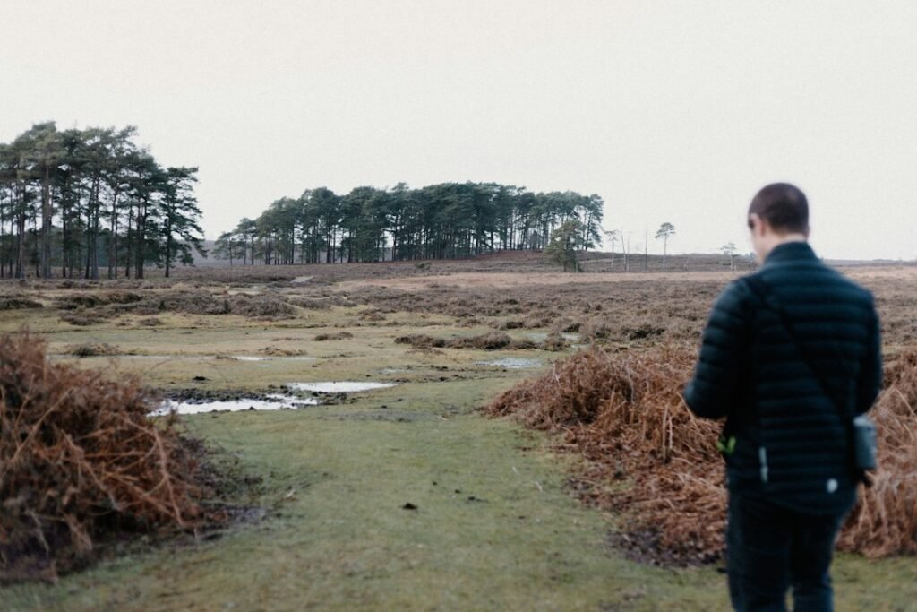 Person standing in an open field considering a decision in daylight
