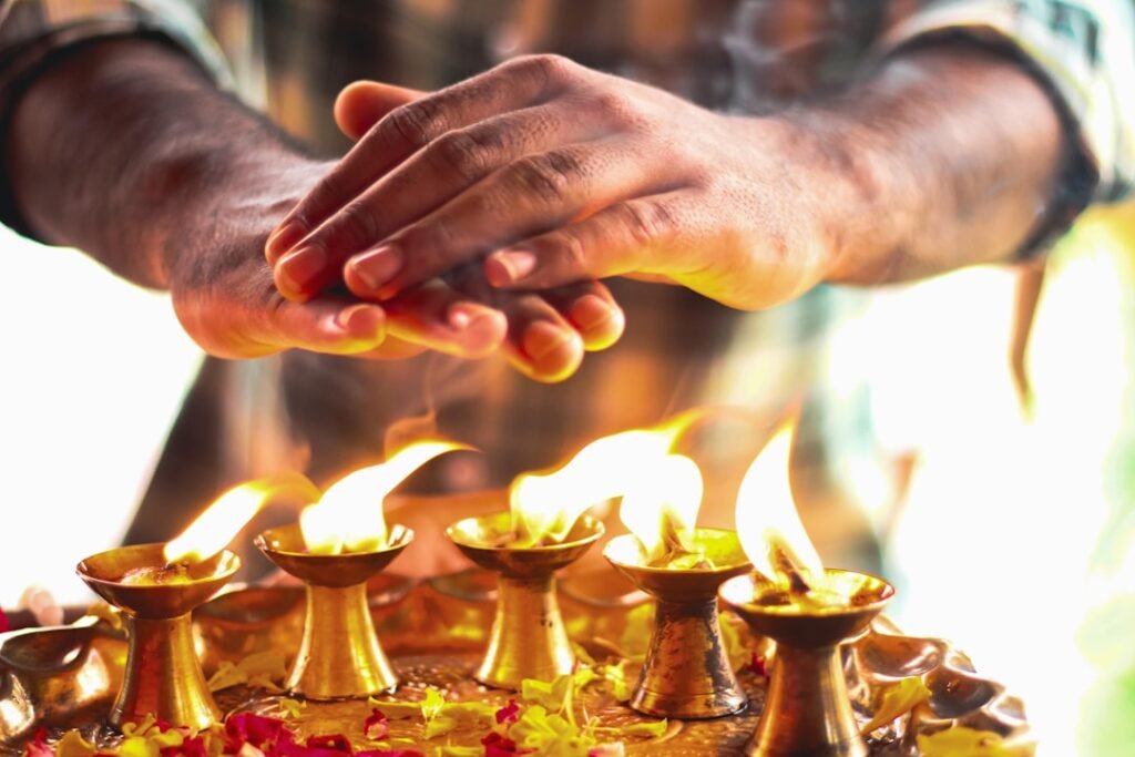 Hands offering a simple home ritual over lit diyas, representing Lal Kitab remedies
