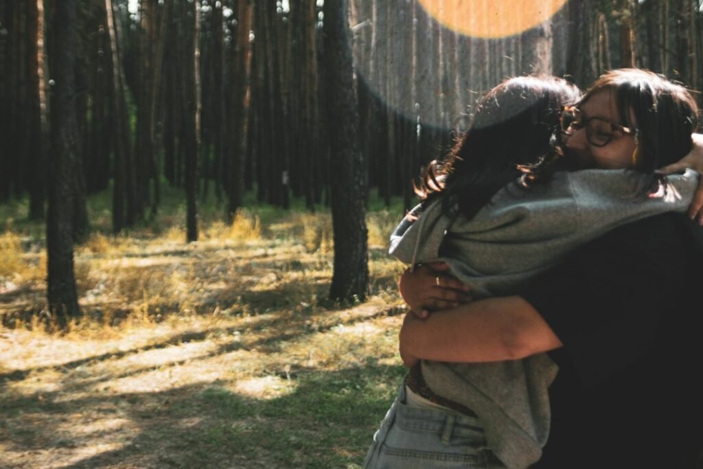 Two people hugging joyfully in a sunlit forest
