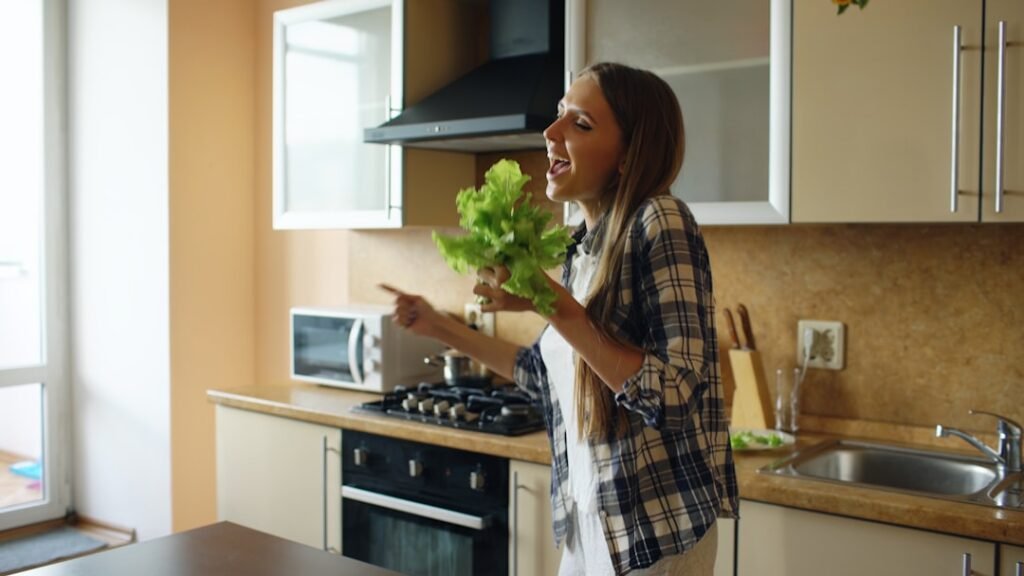Woman happily cooking breakfast in daylight kitchen at home