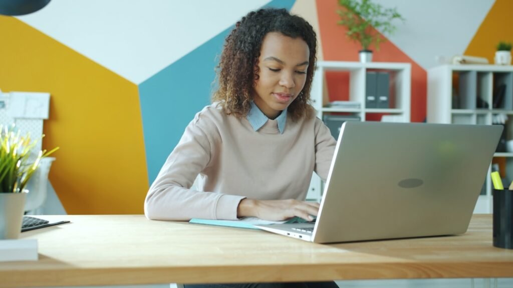 Woman smiling while working on a laptop in daylight