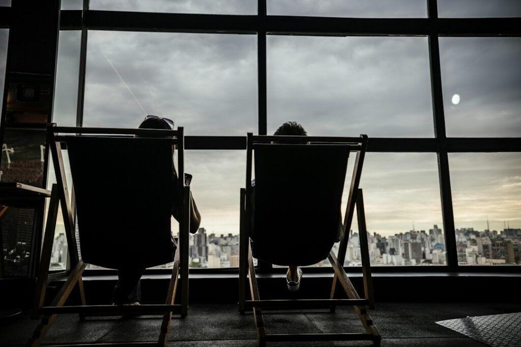 Two people sitting and talking seriously by a window in daylight
