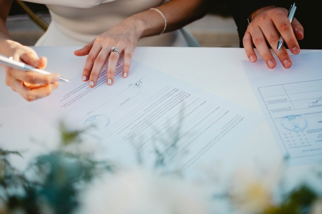 Couple signing marriage documents at a table in daylight