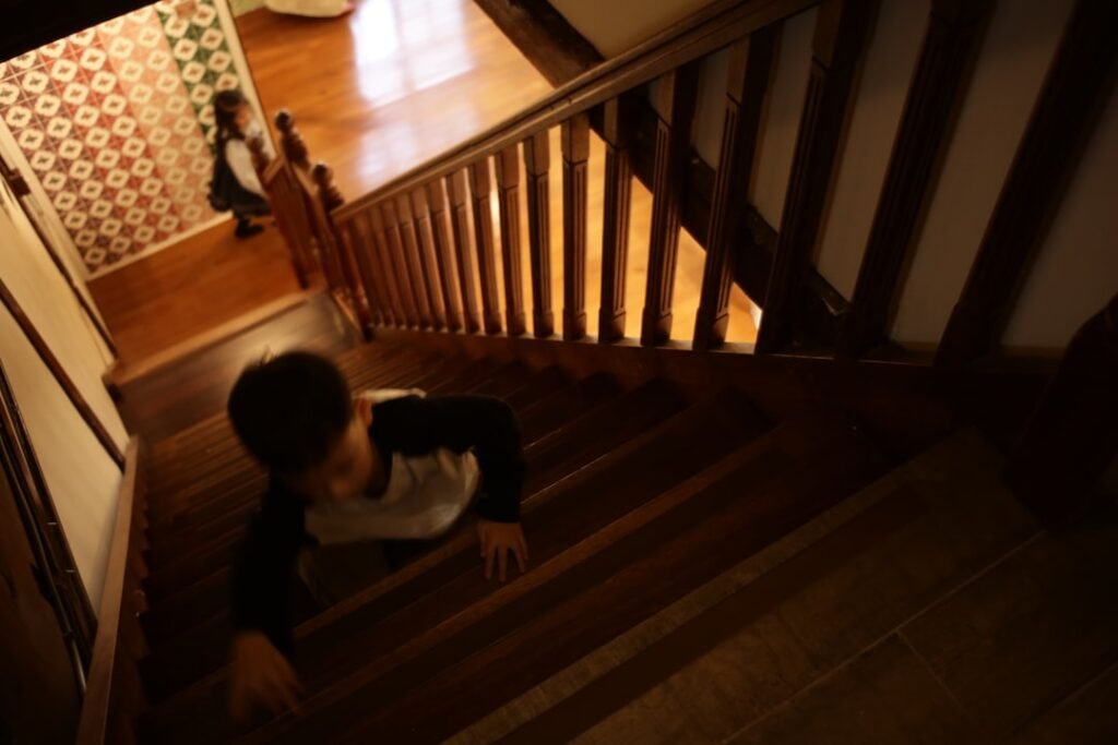 boy crawling up wooden stairs home