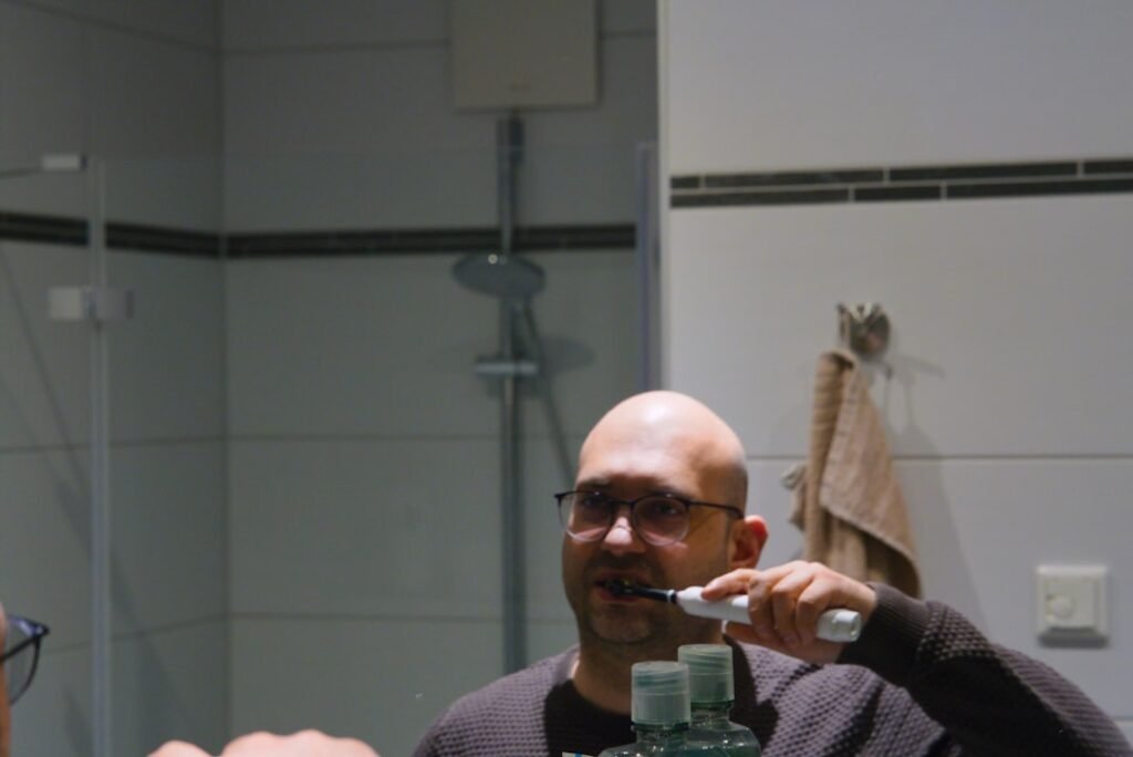 man brushing teeth bathroom mirror daylight