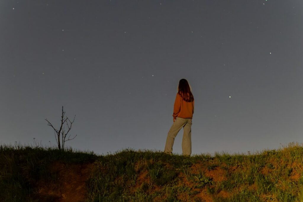 Person looking up at a starry night sky, contemplating the stars