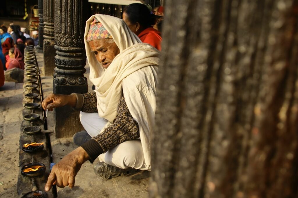 Elderly person lighting oil lamps at a temple, representing Sade Sati remedies
