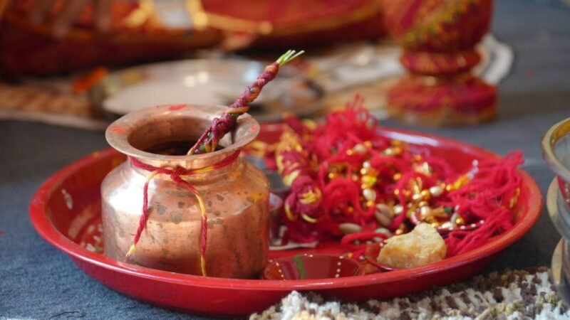 Traditional pooja thali with a copper pot, red thread and offerings arranged for Karwa Chauth