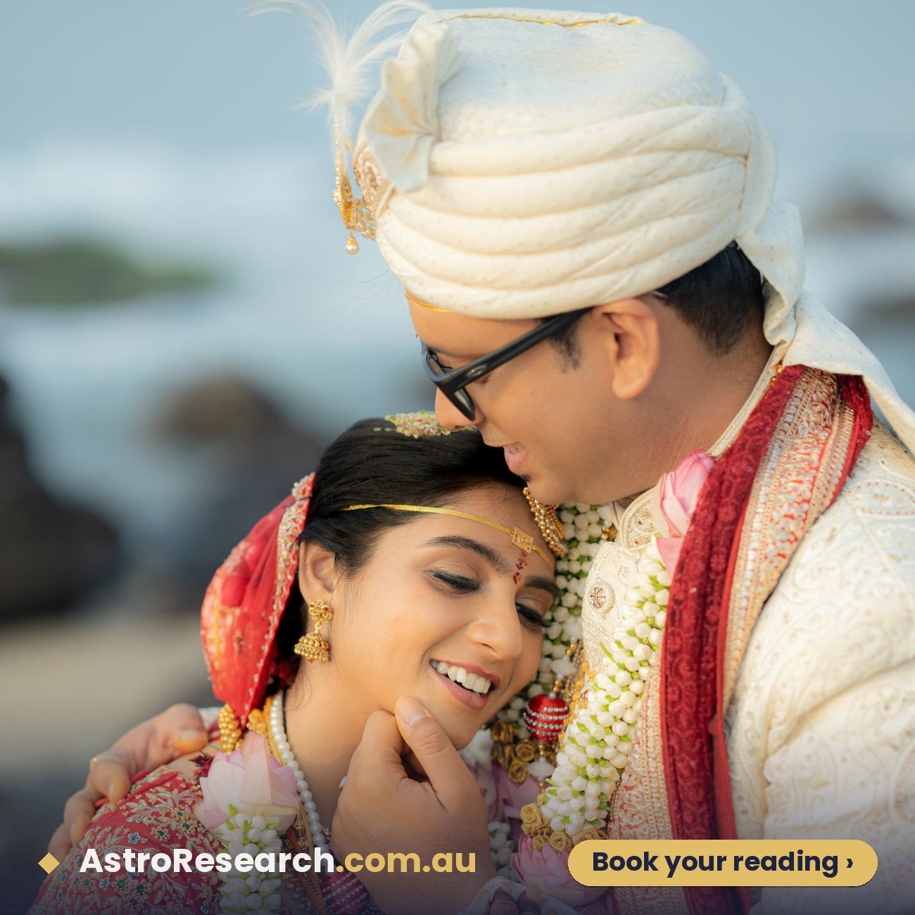 Couple in traditional Indian wedding attire embracing at a beachside ceremony