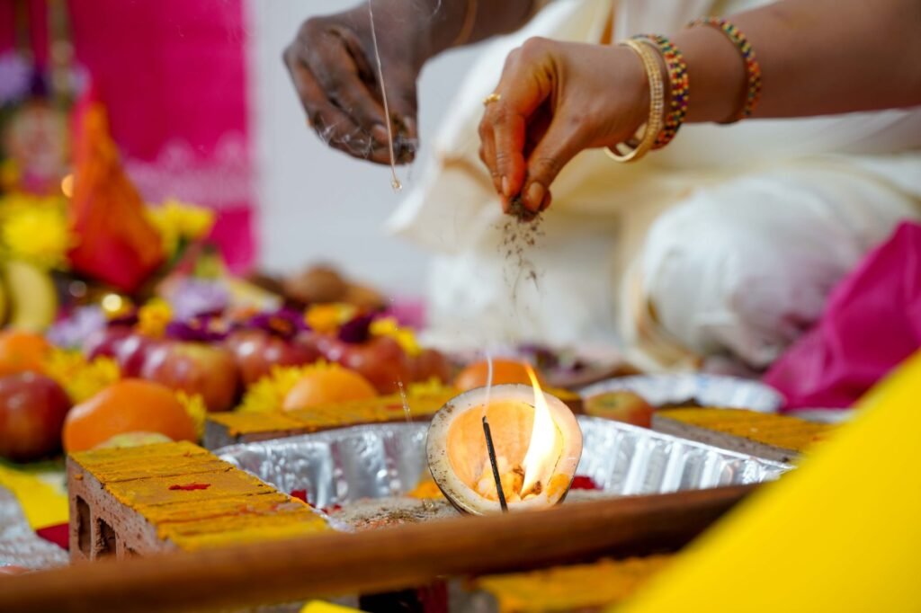 Hands offering fruit and flowers into a sacred fire during a Hindu puja