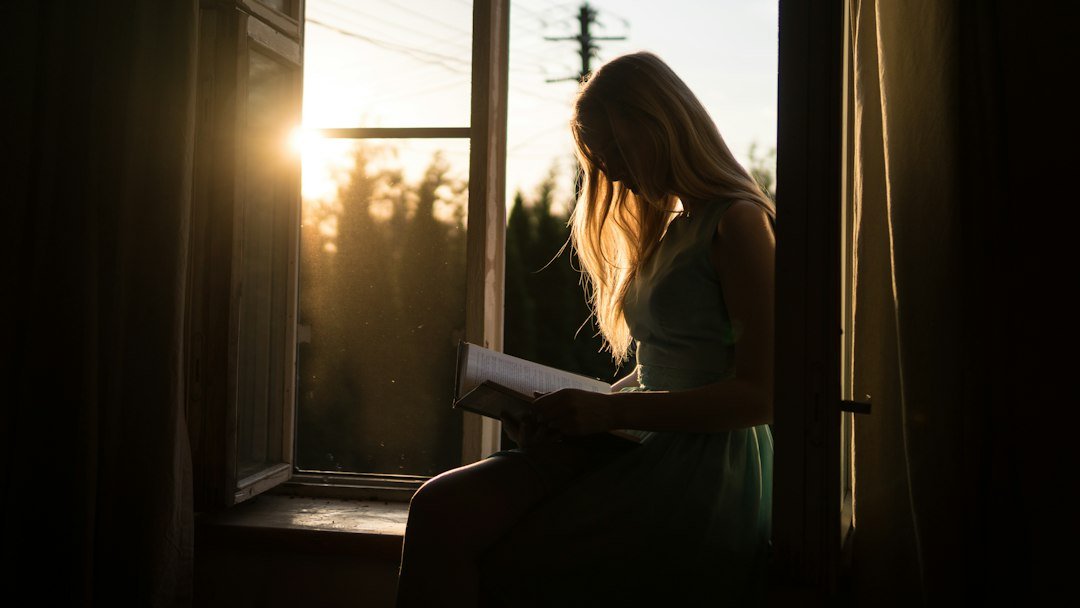 Woman reading by a sunlit window, reflecting on her Vedic astrology reading in Perth, Western Australia